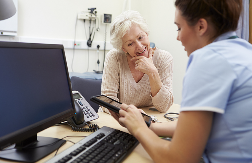 elderly woman smiling while listening to her doctor