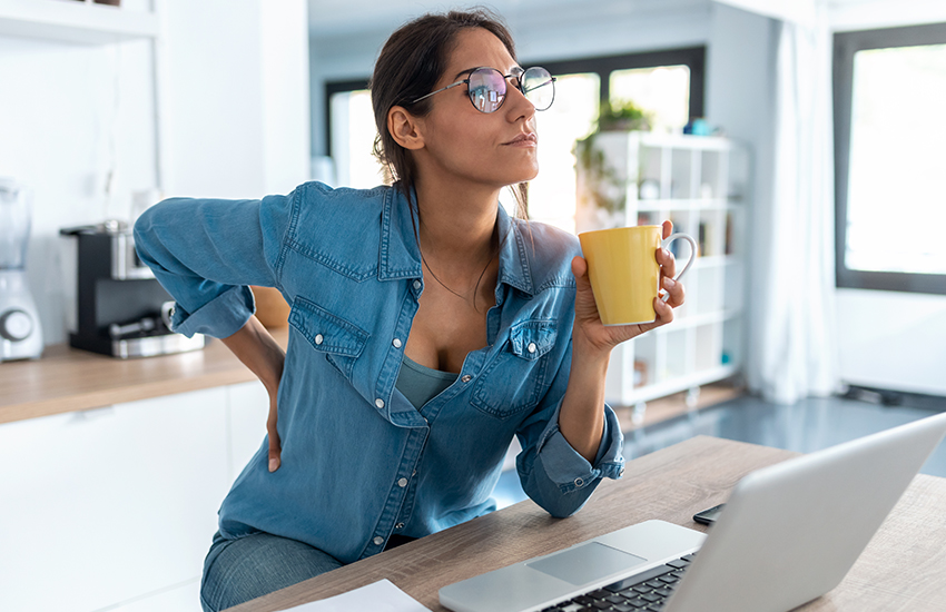 woman at her counter holding her lower back in pain
